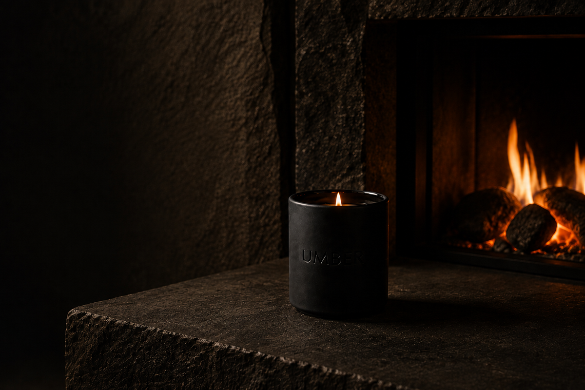 An UMBER candle burning on dark stone beside an open fire